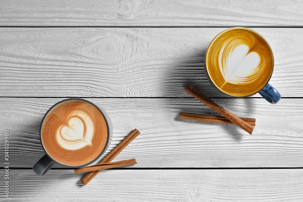 Top view of cups of coffee latte with cinnamons on white wooden background..