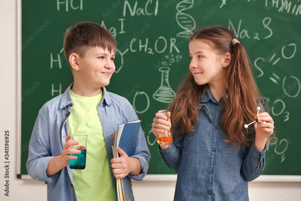 Cute little children near blackboard at chemistry lesson in classroom