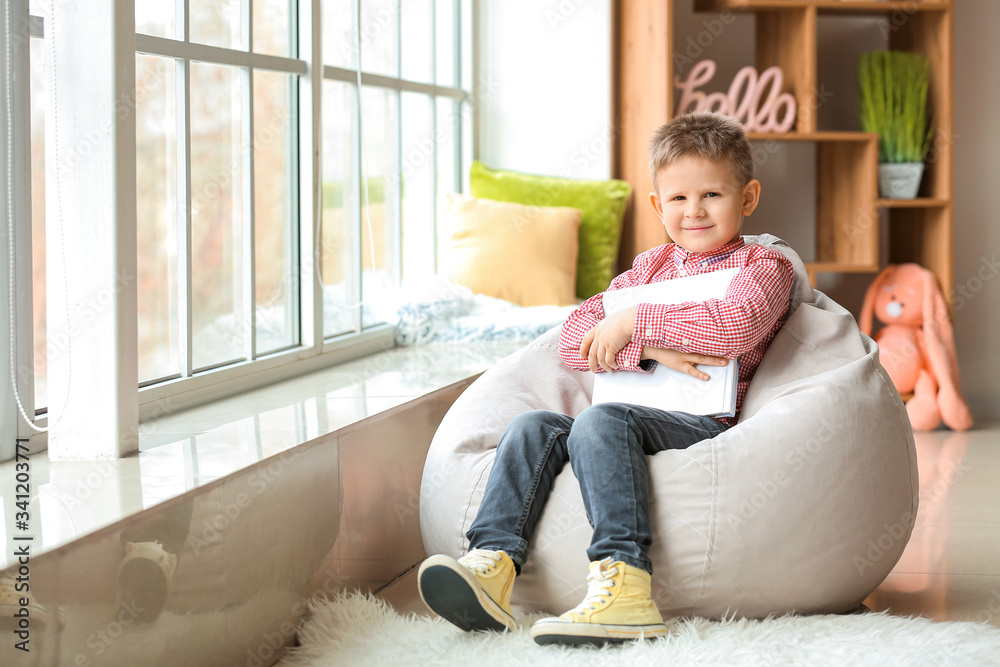 Cute little boy with book at home