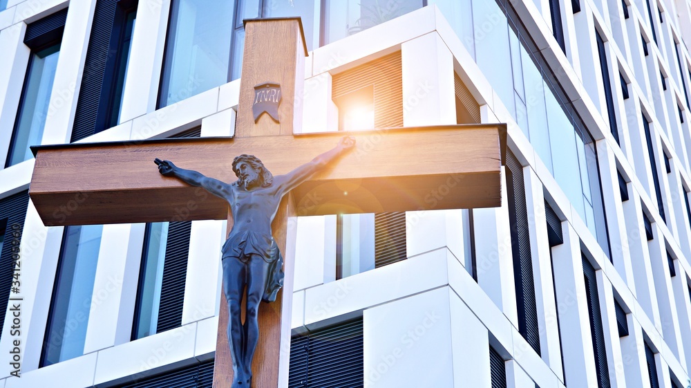 A cross with a figurine of Jesus against the background of the modern office building. The concept o