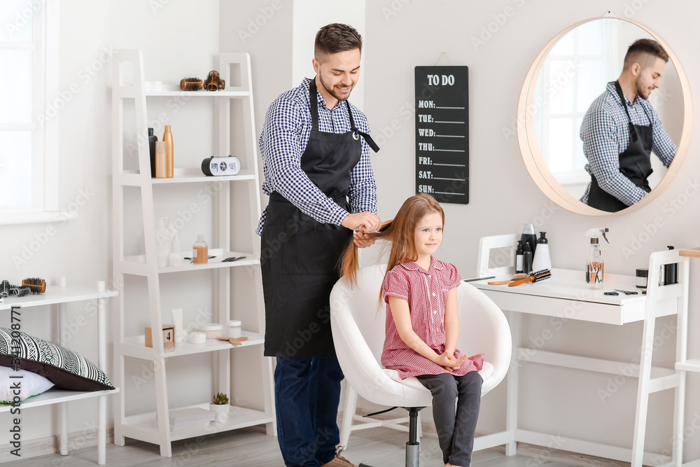 Hairdresser working with little girl in salon