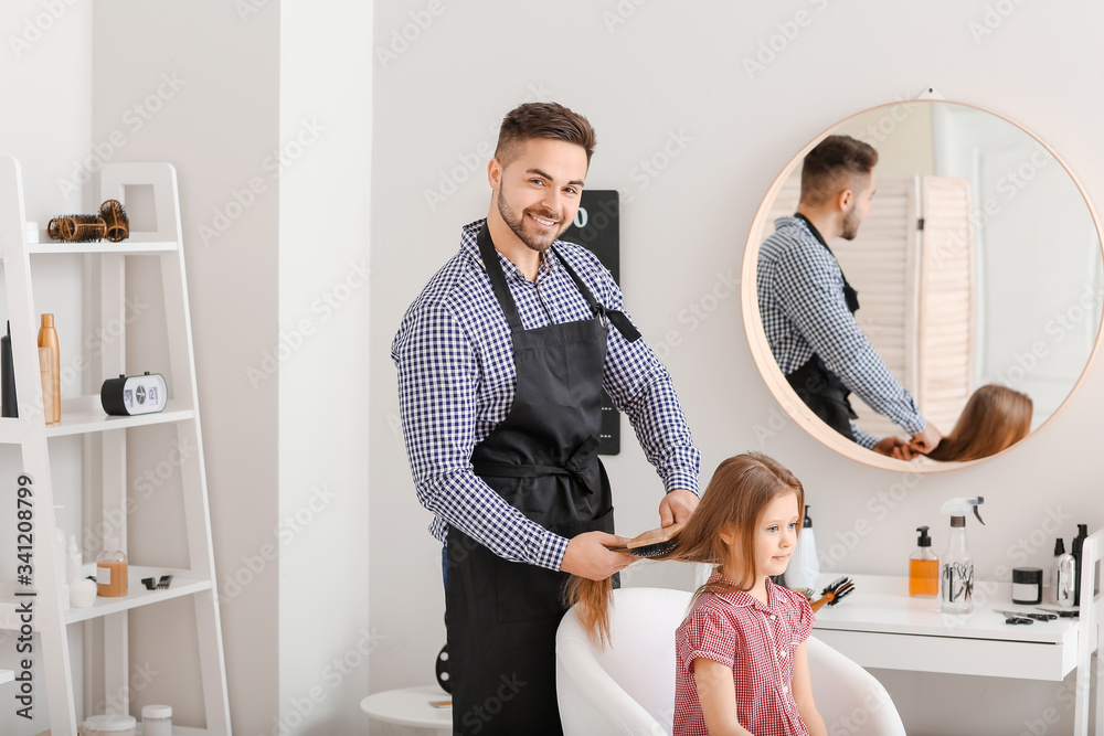 Hairdresser working with little girl in salon