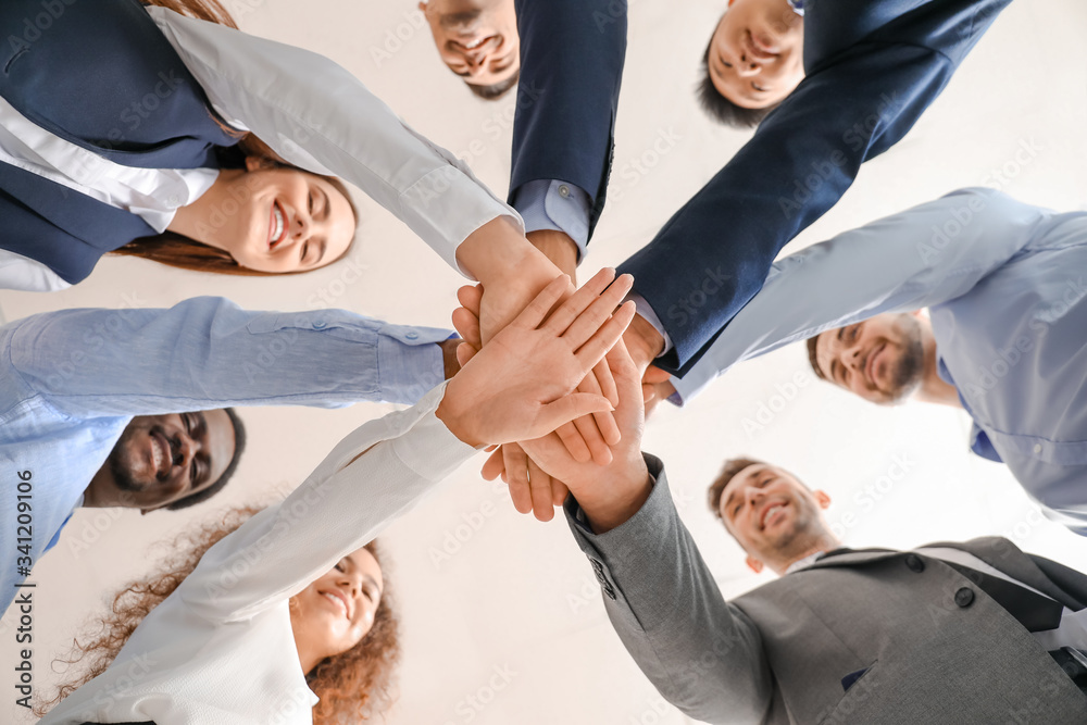 Group of business people putting hands together in office, bottom view. Unity concept