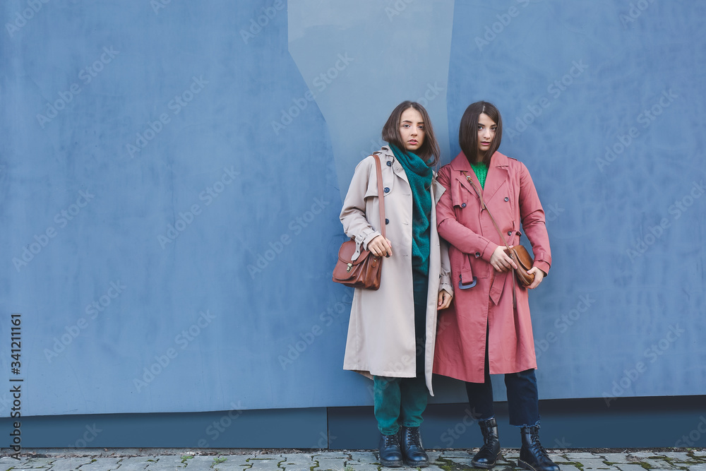 Stylish young women near wall outdoors