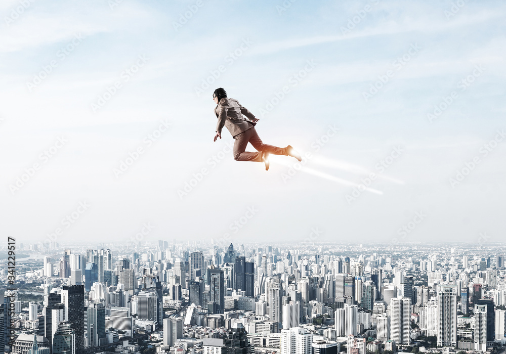 Businessman in suit and aviator hat flying in sky