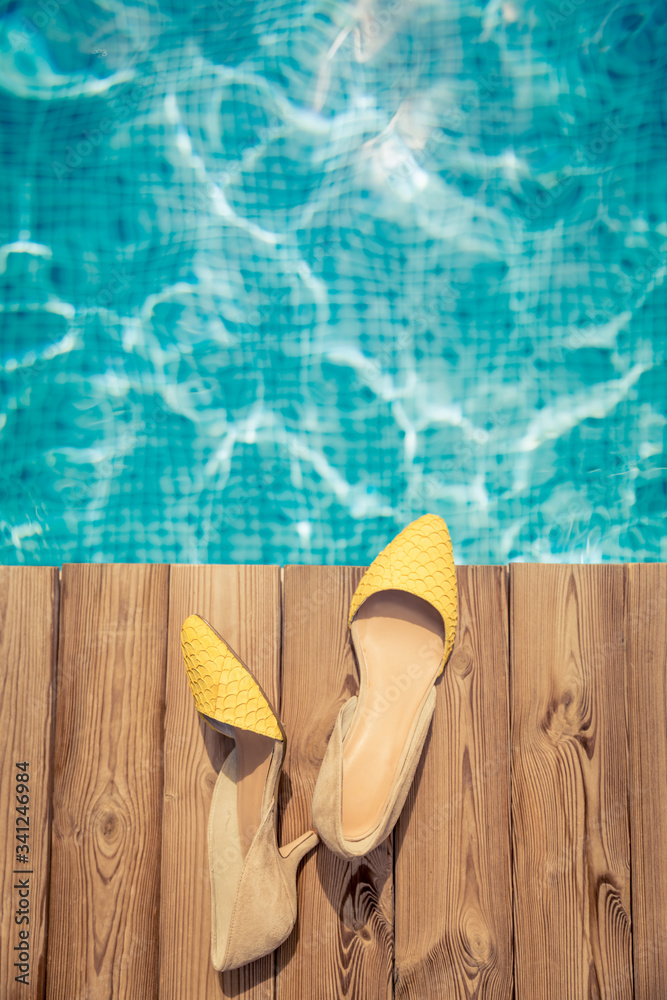 Womans shoes on wooden background near swimming pool