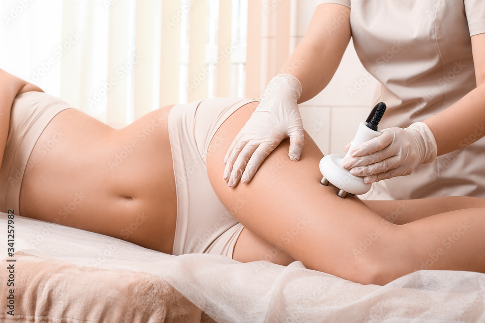 Beautiful woman undergoing procedure of anti-cellulite massage in beauty salon