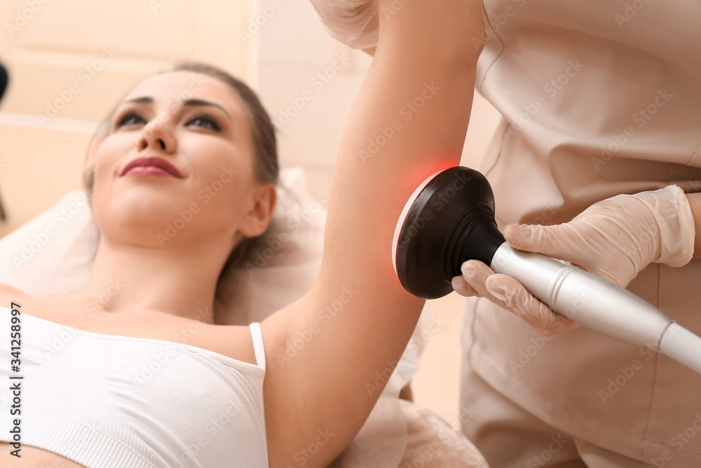 Beautiful woman undergoing procedure of anti-cellulite massage in beauty salon