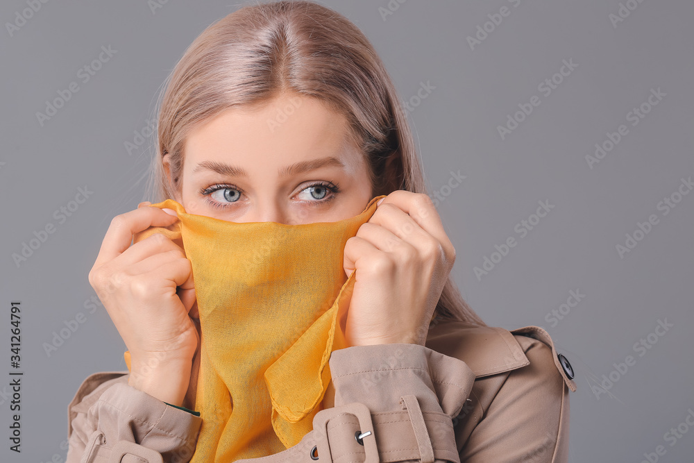 Beautiful young woman with stylish scarf on grey background