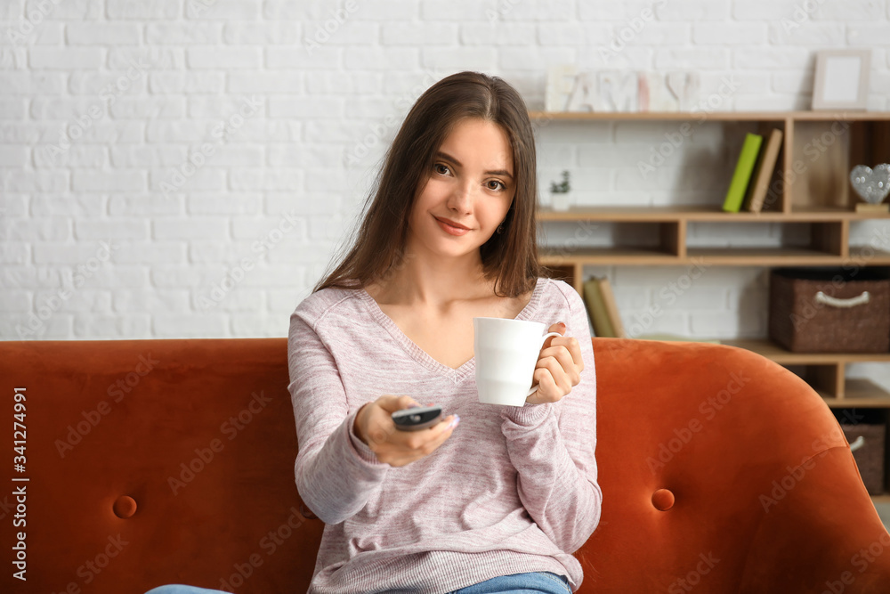 Beautiful young woman watching TV at home