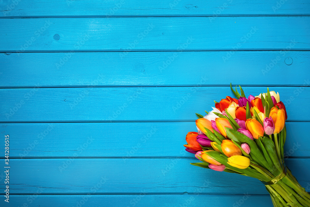 Colorful bouquet of tulips on blue wooden background. Spring flowers. Greeting card with copy space 