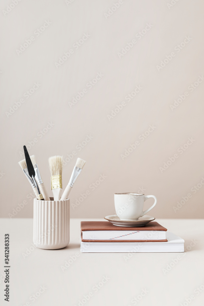 Paintbrushes and cup on top of books