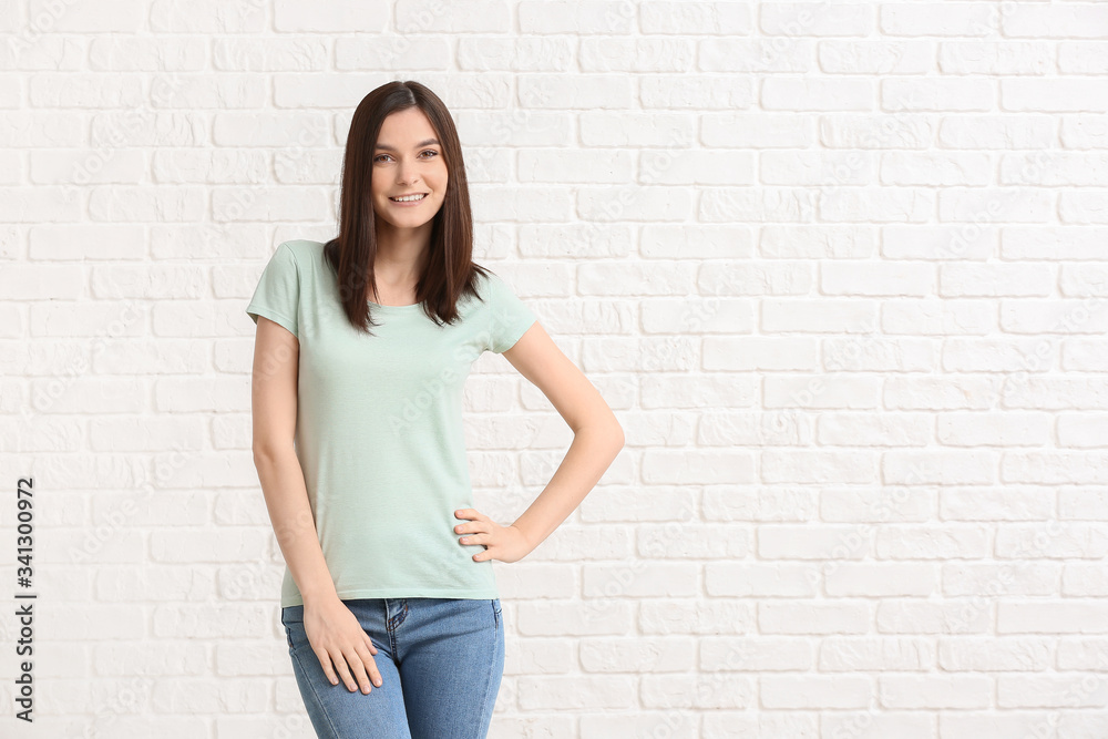 Woman in stylish t-shirt on white brick background