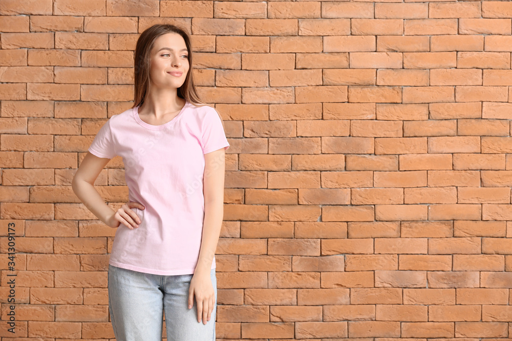 Young woman in stylish t-shirt on brick background