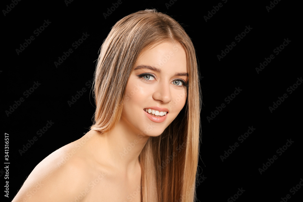 Young blonde with beautiful hair on dark background