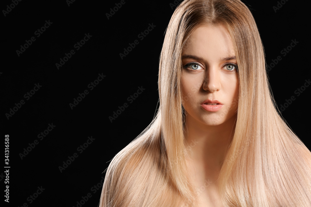 Young blonde with beautiful hair on dark background