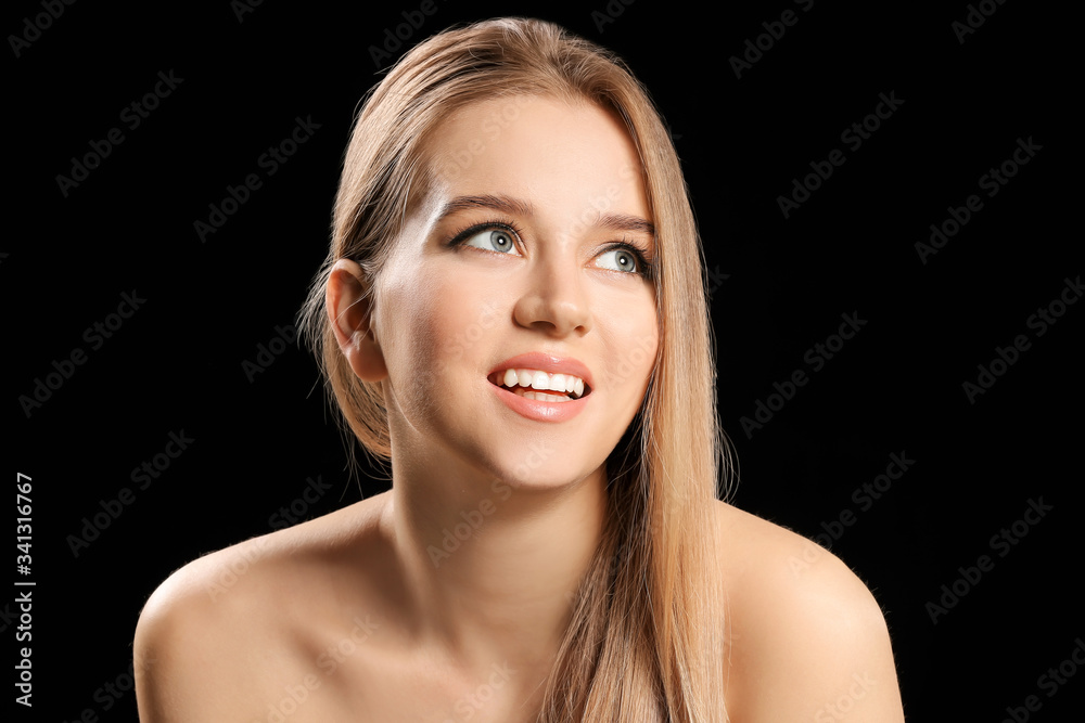 Young blonde with beautiful hair on dark background