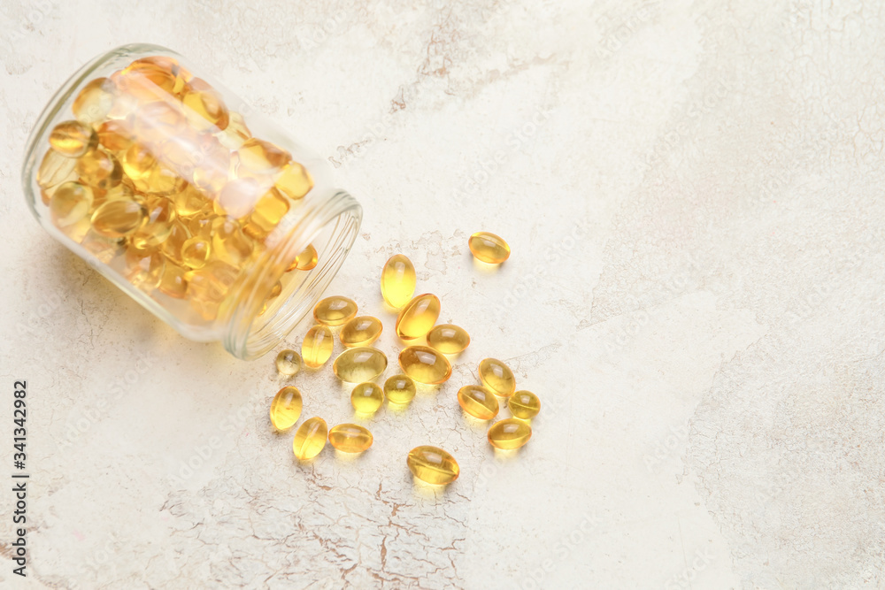 Jar with fish oil capsules on table