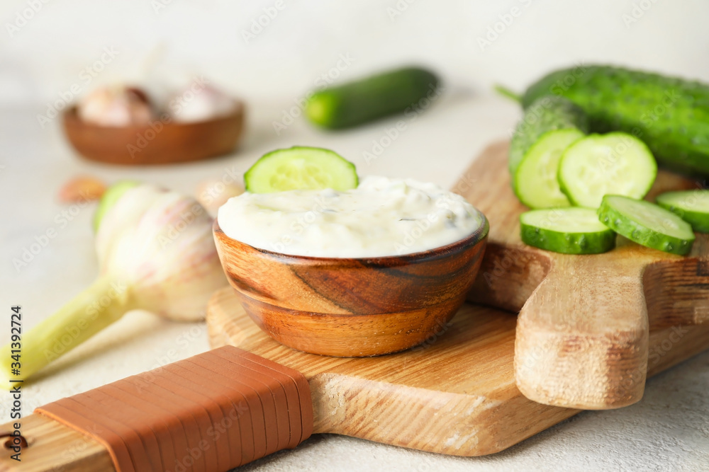 Delicious yogurt sauce with cucumber in bowl on table