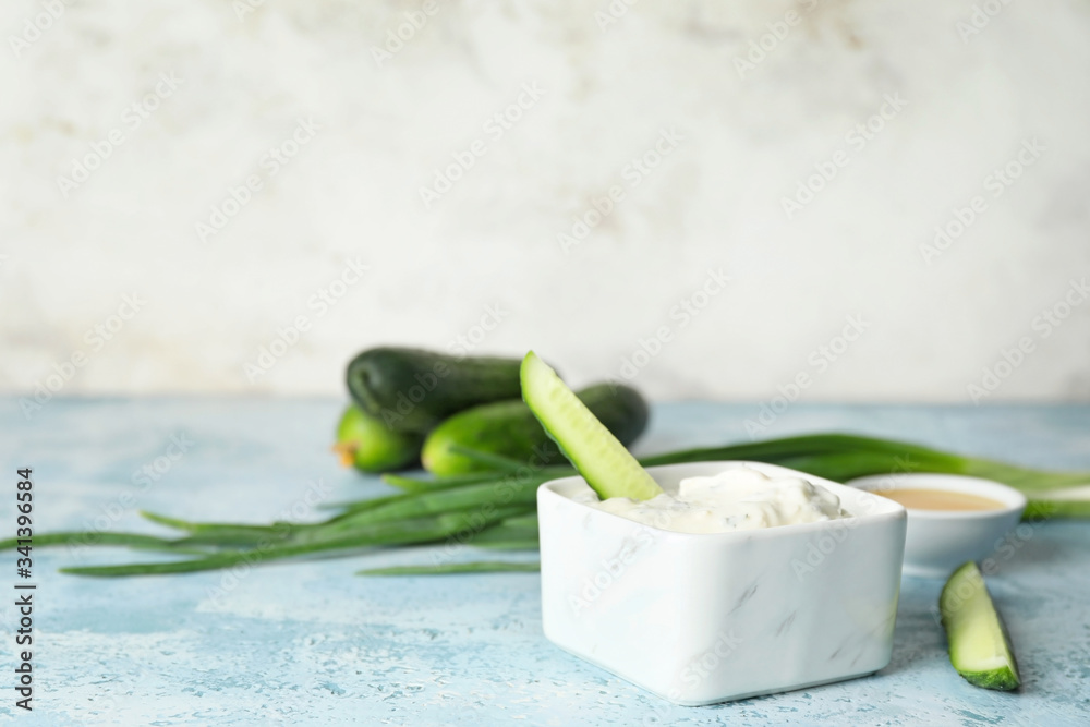 Delicious yogurt sauce with cucumber in bowl on table