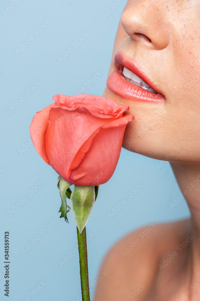 Portrait of a woman with an orange rose on blue background