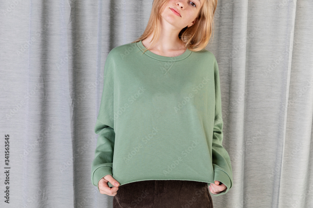 Smart woman wearing green sweater by a curtain