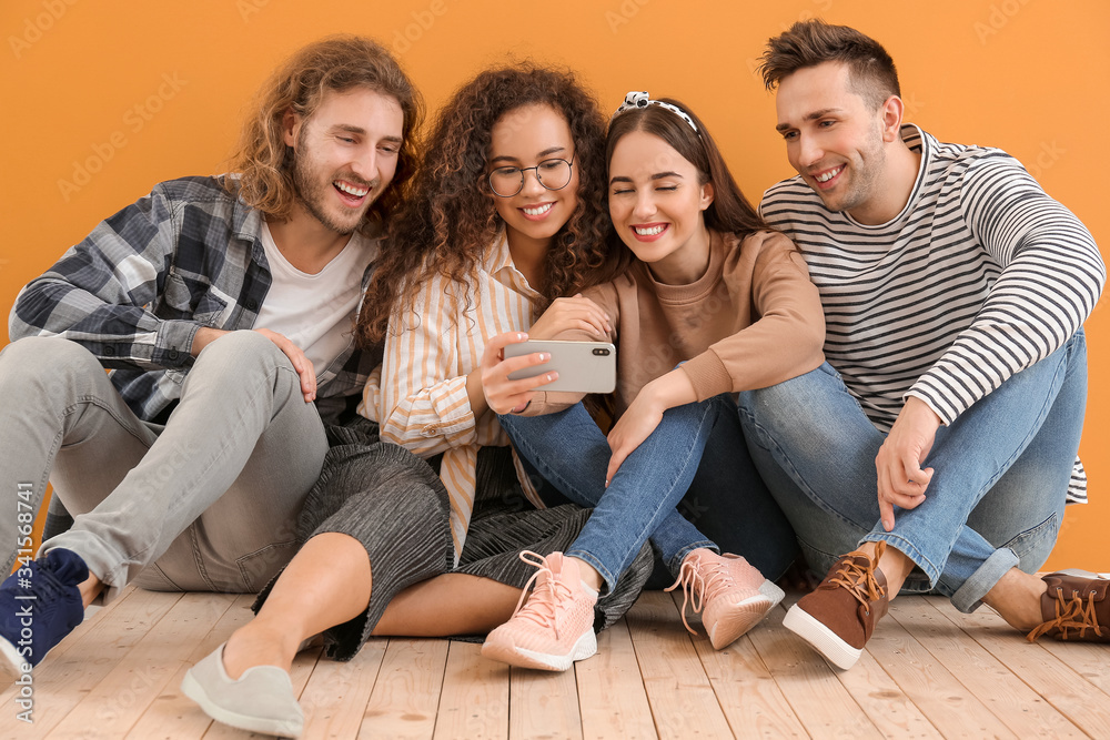 Friends taking selfie near color wall