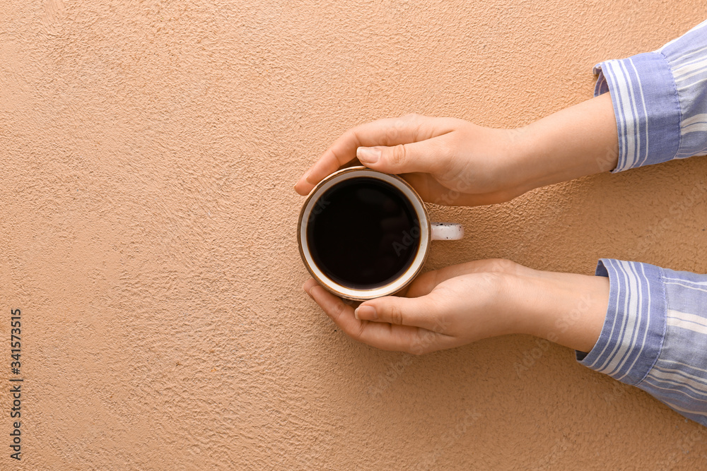 Female hands with cup of hot coffee on color background, top view