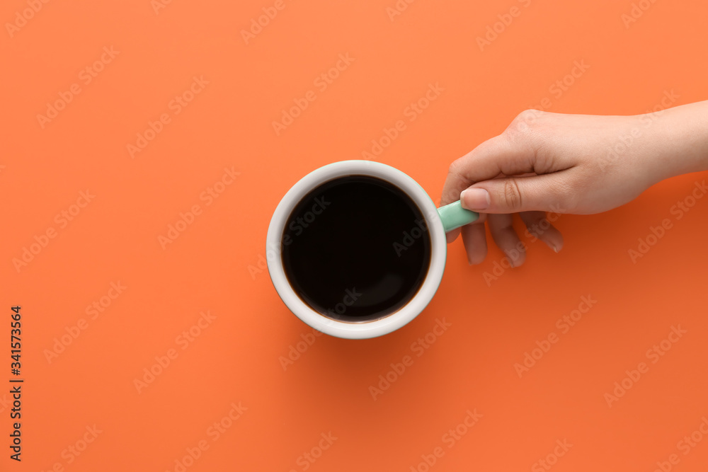 Female hand with cup of hot coffee on color background, top view