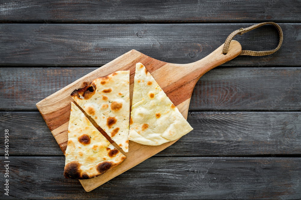 Make focaccia. Traditional italian bread on cutting board on dark wooden table top-down copy space