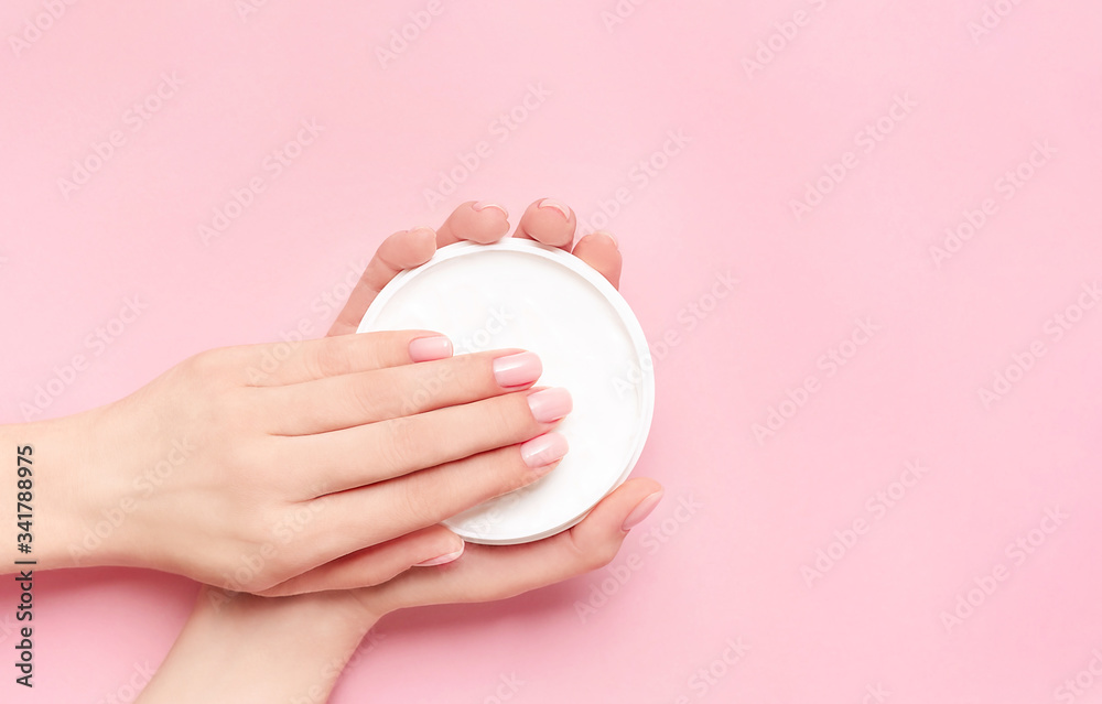 Creative image of woman moisturizing her hands with cosmetic cream with copy space on pink backgroun