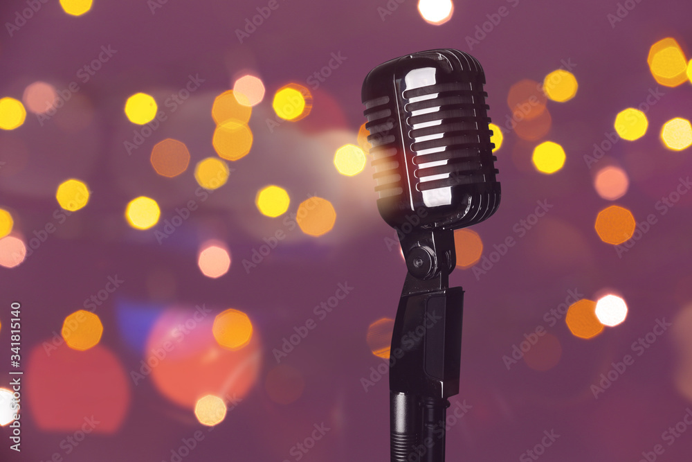 Retro microphone on color background with blurred lights