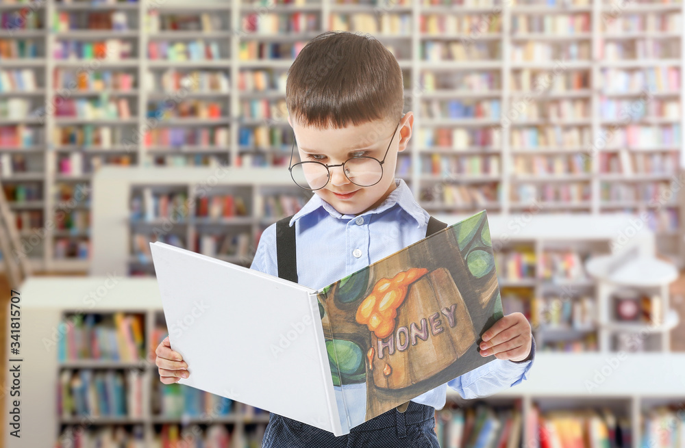 Cute little boy with book in modern library