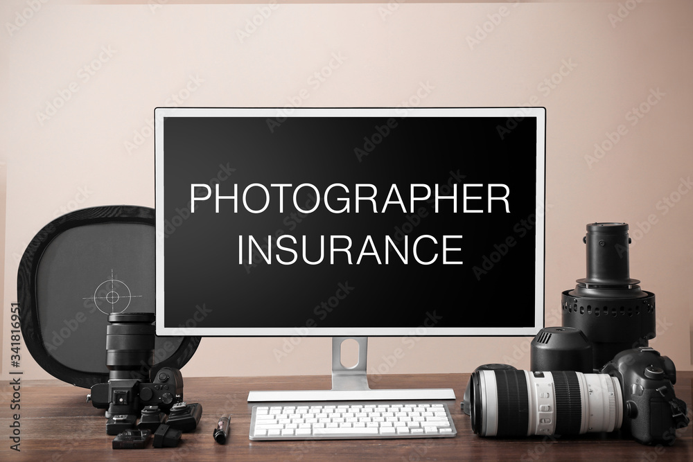 Modern professional equipment and computer with text PHOTOGRAPHER INSURANCE on table