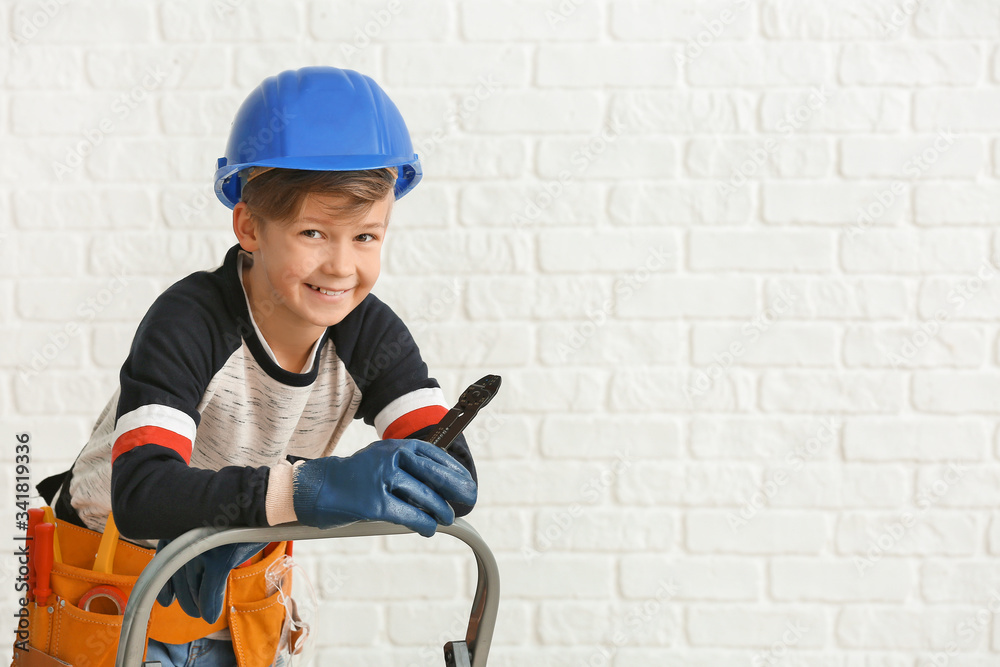 Cute little electrician on white brick background