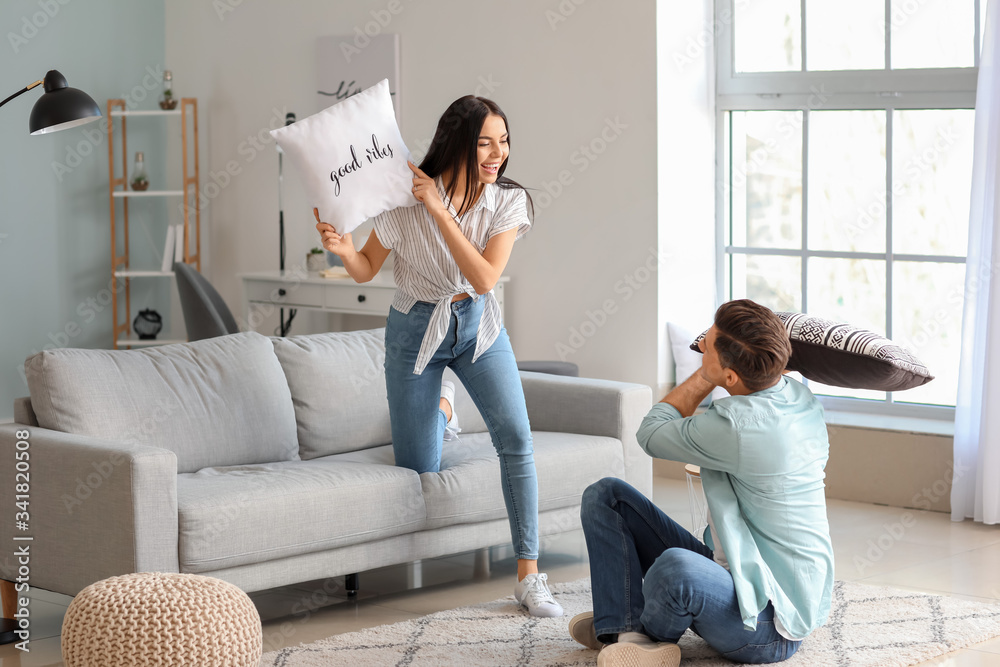 Happy young couple fighting on pillows at home