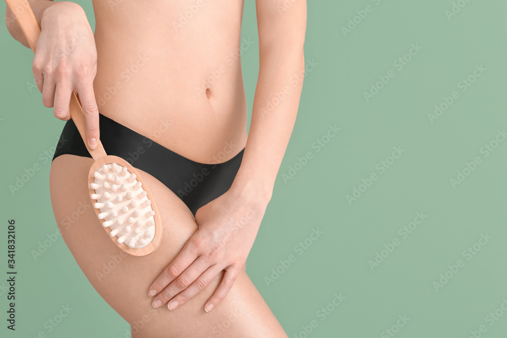 Woman with anti-cellulite massage brush on color background