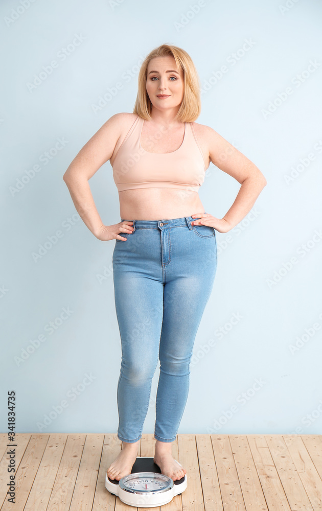 Overweight woman with scales on color background. Weight loss concept