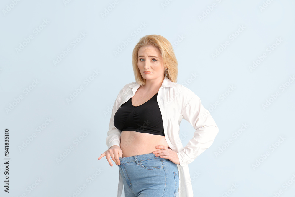 Sad overweight woman on color background