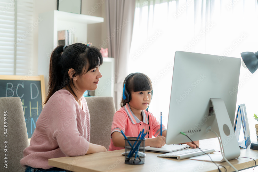 Asian girl student with mother video conference e-learning with teacher on computer in living room a