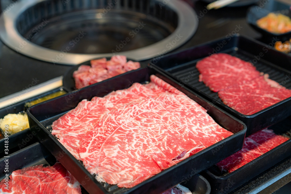 Plates of raw meat such as Premium quality raw sliced wagyu beef, pork, sushi and dipping sauce. Pre