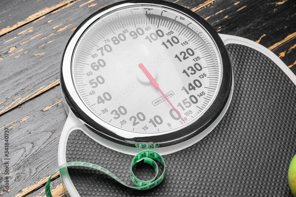 Weight scales with measuring tape on wooden background. Slimming concept