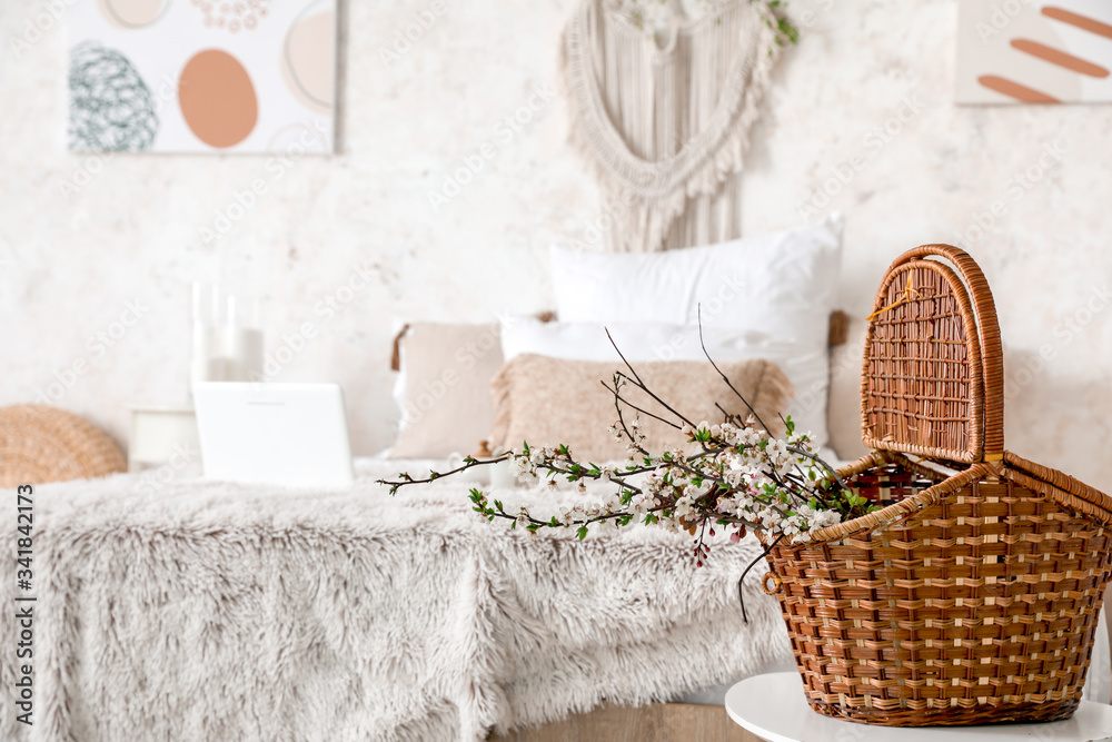 Wicker basket with spring tree branches in interior of bedroom