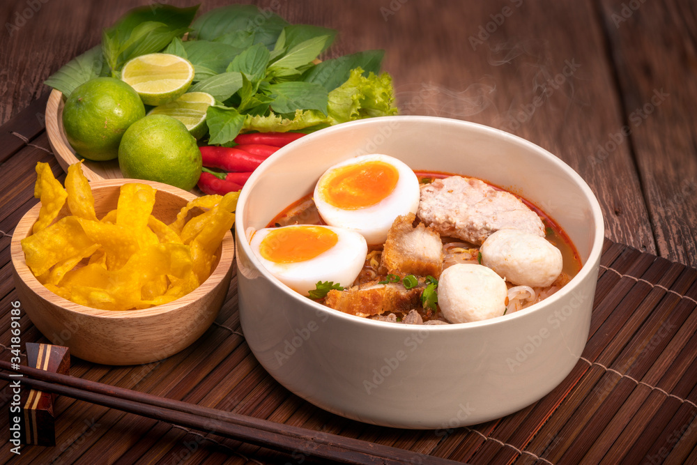 Spicy Noodles with Egg, fish ball and minced pork, Spicy Pork noodle with Spicy soup on wood backgro