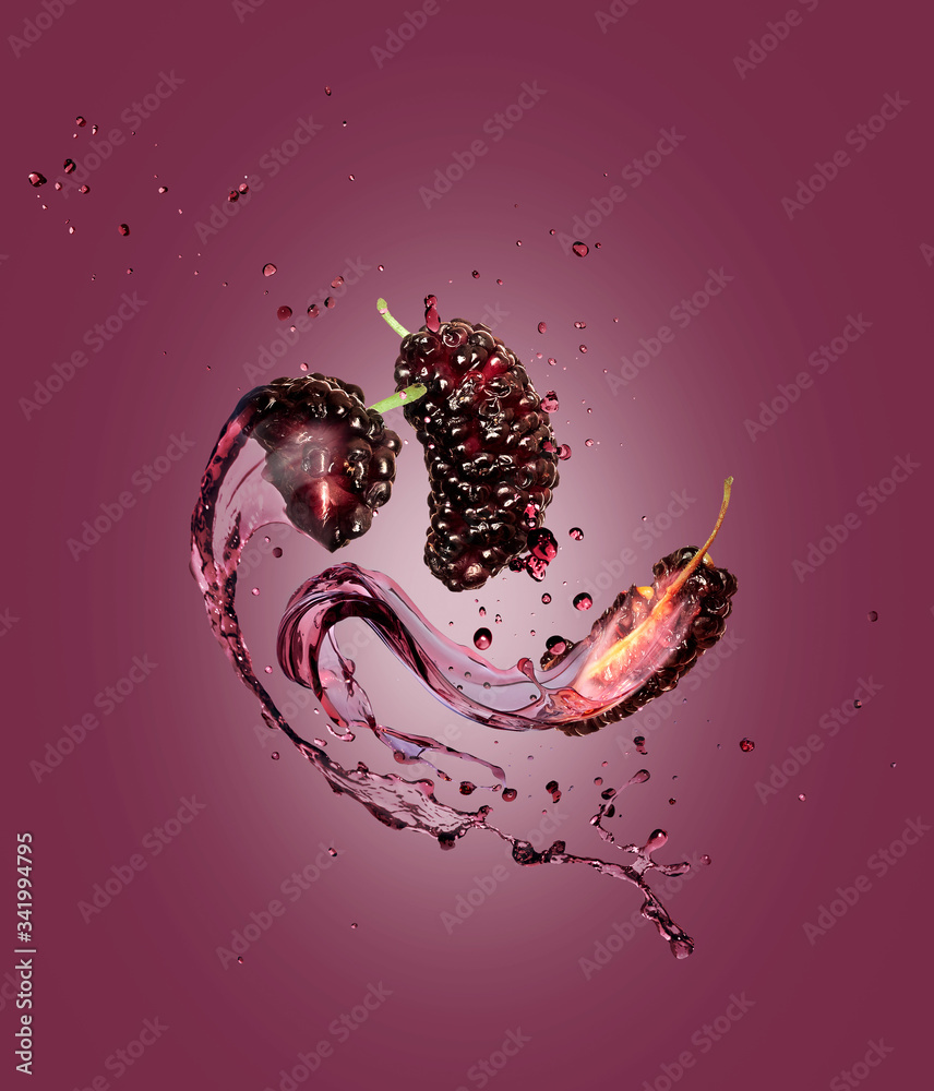 Juice splashes out from torn mulberries on a purple background