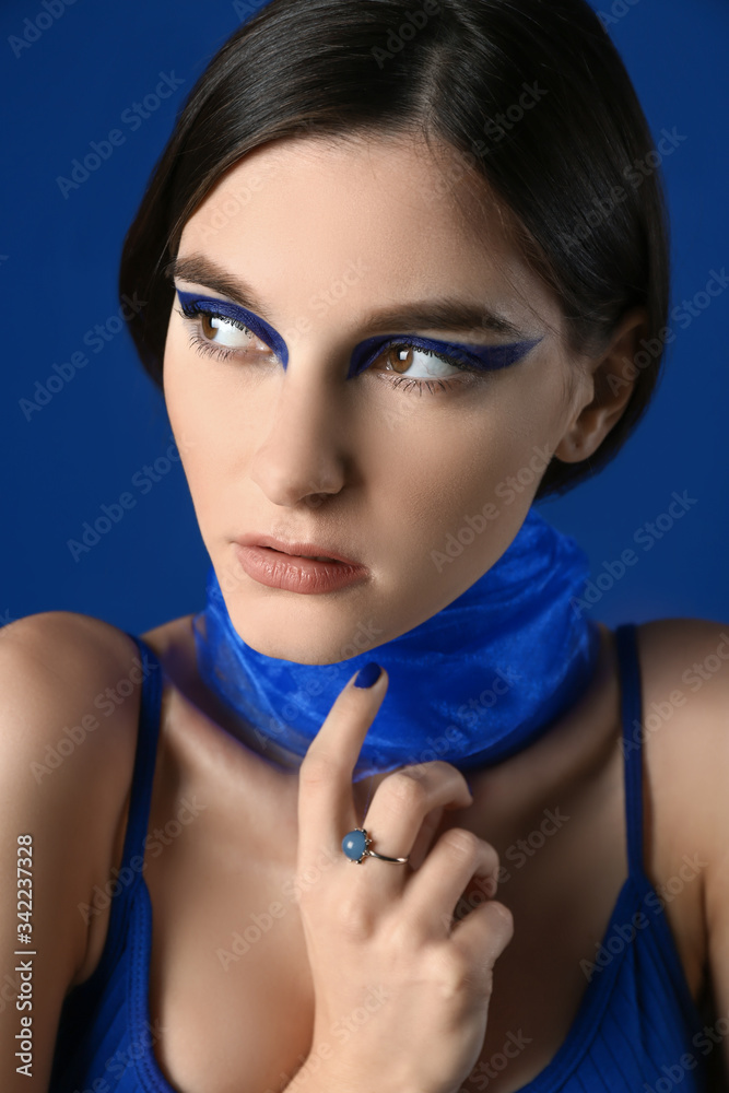 Portrait of fashionable young woman with veil on blue background