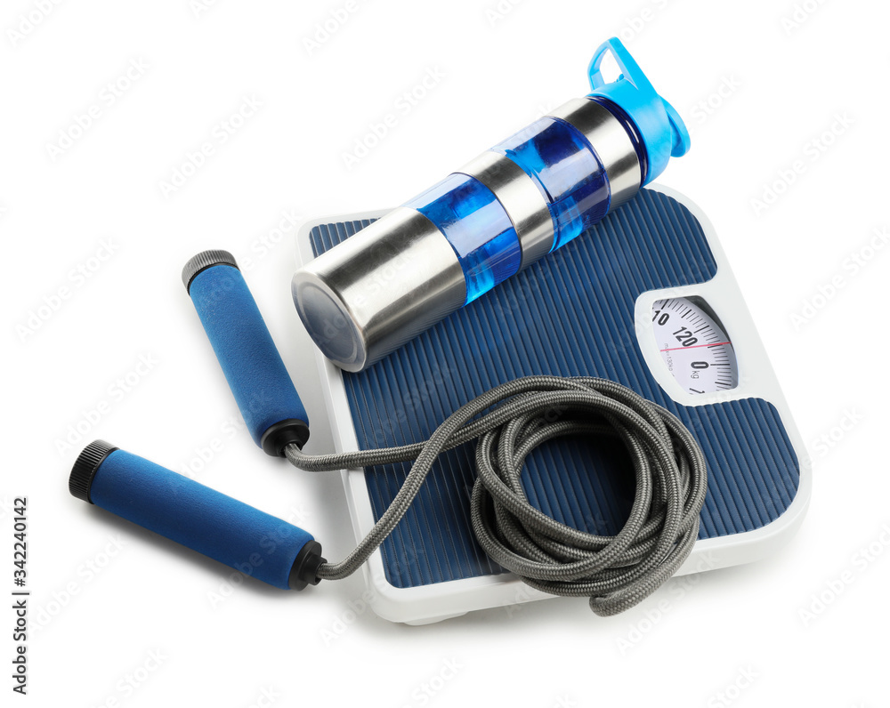 Weight scales with bottle of water and jumping rope on white background. Slimming concept