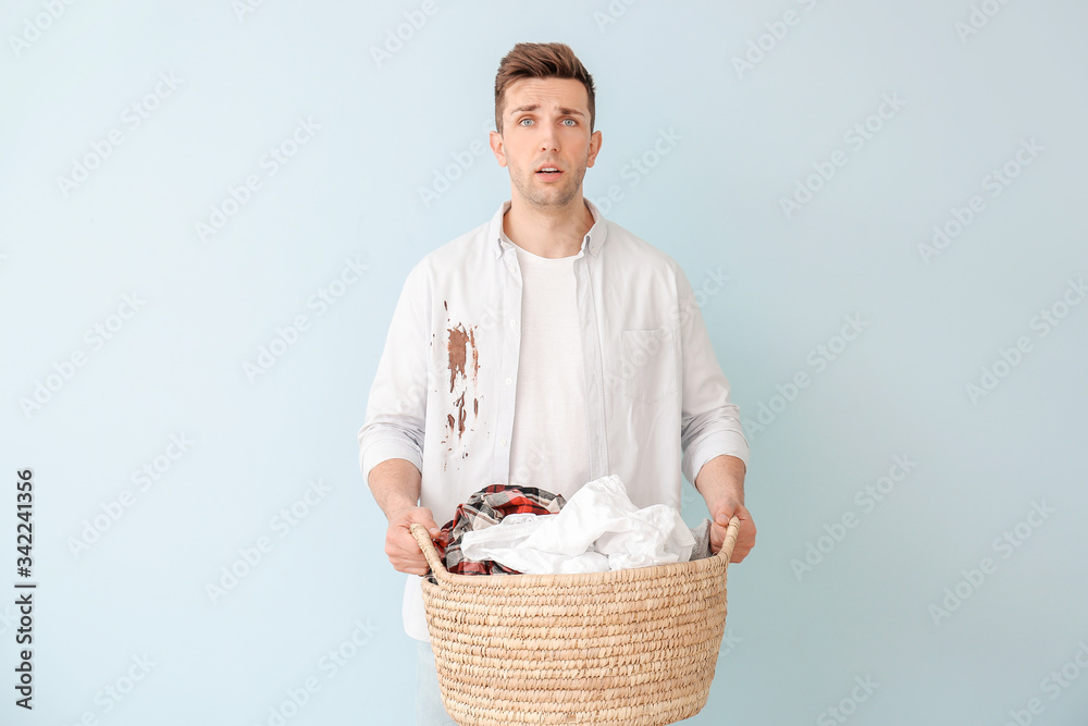 Troubled man with dirty clothes on color background