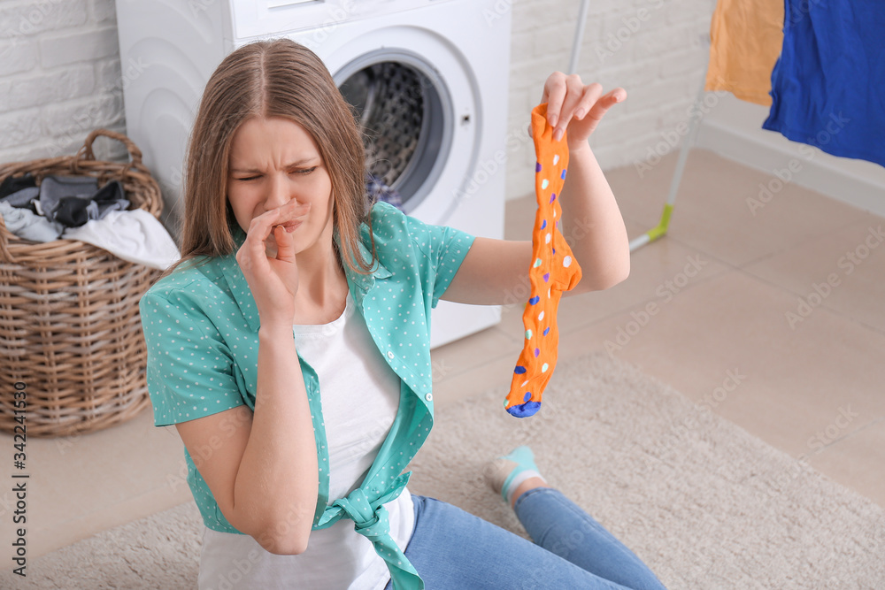 Displeased woman doing laundry in bathroom