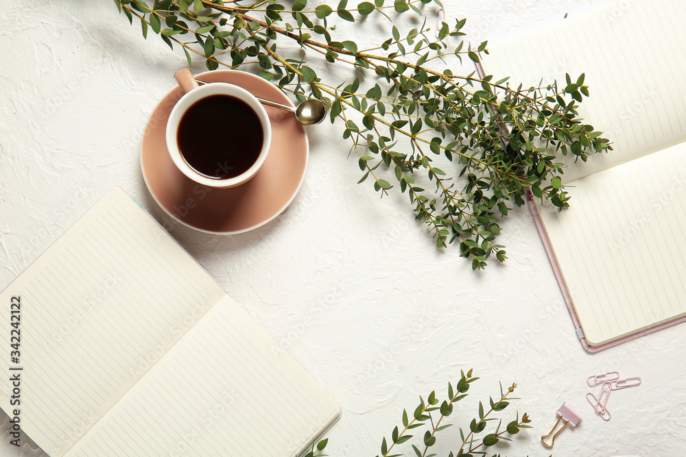 Cup of coffee and notebooks on light background